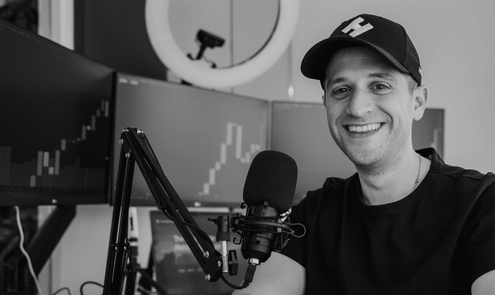 Jordan Fried at his desk with a podcast microphone and market charts